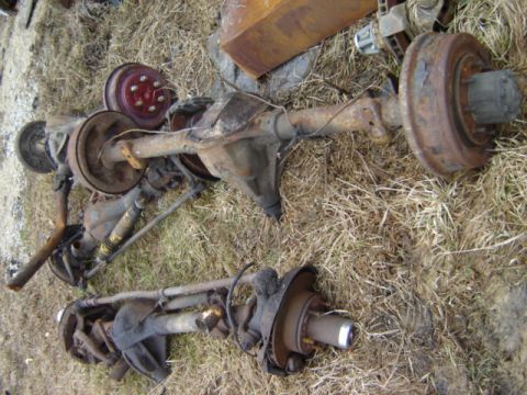 1992 Ford Bronco - Two old truck axles are shown on the ground, appearing to be parts for a vehicle.