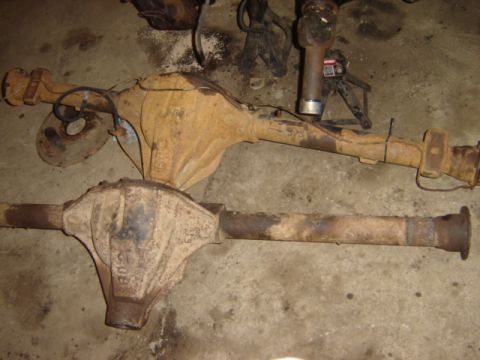 1992 Ford Bronco - Two heavily rusted vehicle rear axles are shown laid out on a concrete floor, with some parts in the background.