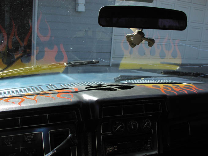 Interior dash view from the driver seat showing flame paint on the cowl and gauge cluster