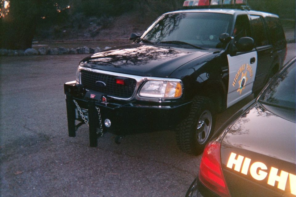 Black and white Highway Patrol SUV with brush guard parked beside a patrol sedan