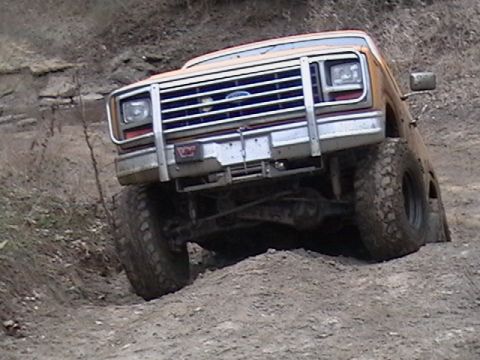 1986 Ford Bronco - This Ford truck is navigating a dirt hill with its front tires angled.