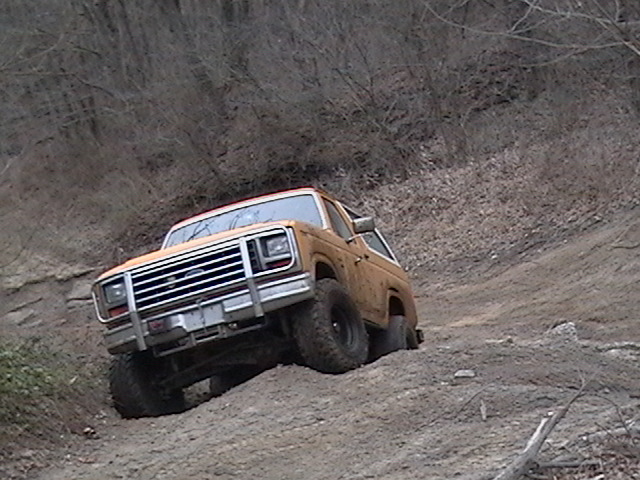 Orange SUV with chrome grille and bumper driving on a dirt hill