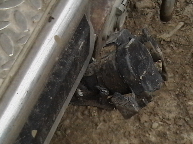 Close-up of a dirty, black mechanical part attached to a silver metal bar