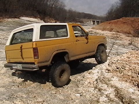 1986 Ford Bronco - This SUV is navigating a rough, rocky landscape with a bridge visible in the background.