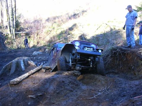1990 Ford Bronco - Off-road Jeep navigates a challenging muddy terrain with onlookers present.