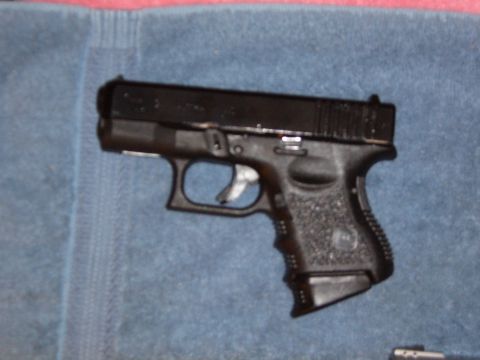 1993 Ford Bronco - A black subcompact polymer-frame semi-automatic pistol with an extended magazine floorplate, laid on its side on a blue fleece blanket.