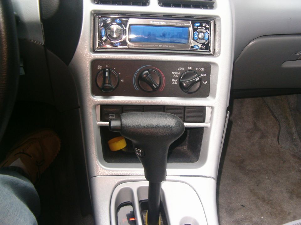 Car interior showing gear shifter, climate controls, and aftermarket stereo