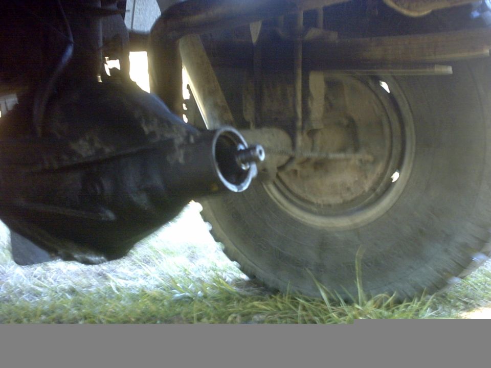 Underside view of a solid axle housing, driveshaft yoke and muddy BFGoodrich tire
