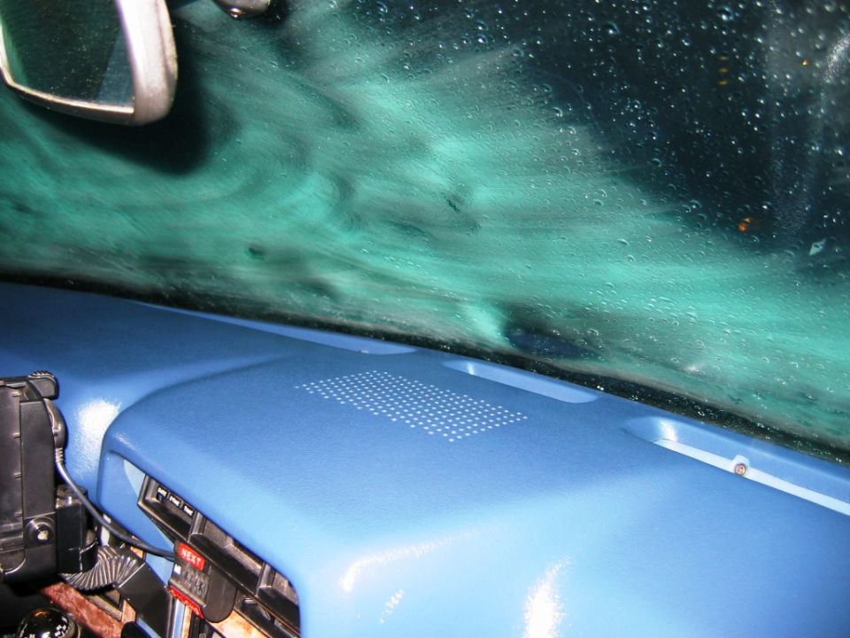 Blue dashboard interior with windshield covered in car-wash suds and water
