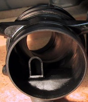 2002 Ford Excursion - Close-up of a black plastic air intake part with a U-shaped obstruction inside.