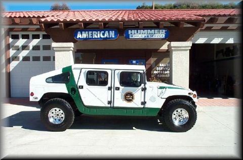 1993 Ford Bronco - A Hummer H1 is parked outside a dealership with "American Hummer Supplies & Service" signage.