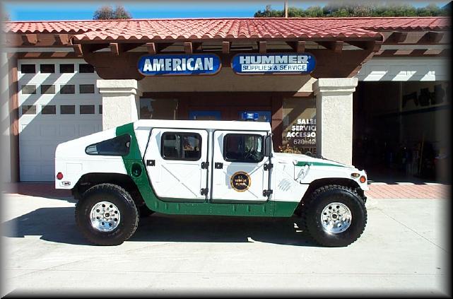 White and green Hummer H1 parked in front of American Hummer Supplies & Service