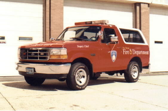Red 1993 Ford Bronco with 'Fire Department' and 'Deputy Chief' text, parked in front of garage doors