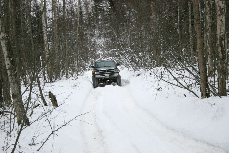 Dodge Ram pickup truck driving on a snowy forest road