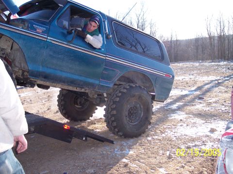 1995 Ford Bronco - This teal Ford Bronco, likely from the late 1970s, is shown being loaded onto a tow ramp with its large off-road tires.