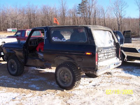 1995 Ford Bronco - A black Ford Bronco, likely from the late 1970s, is parked outdoors with its doors removed and a trailer hitched to the rear.