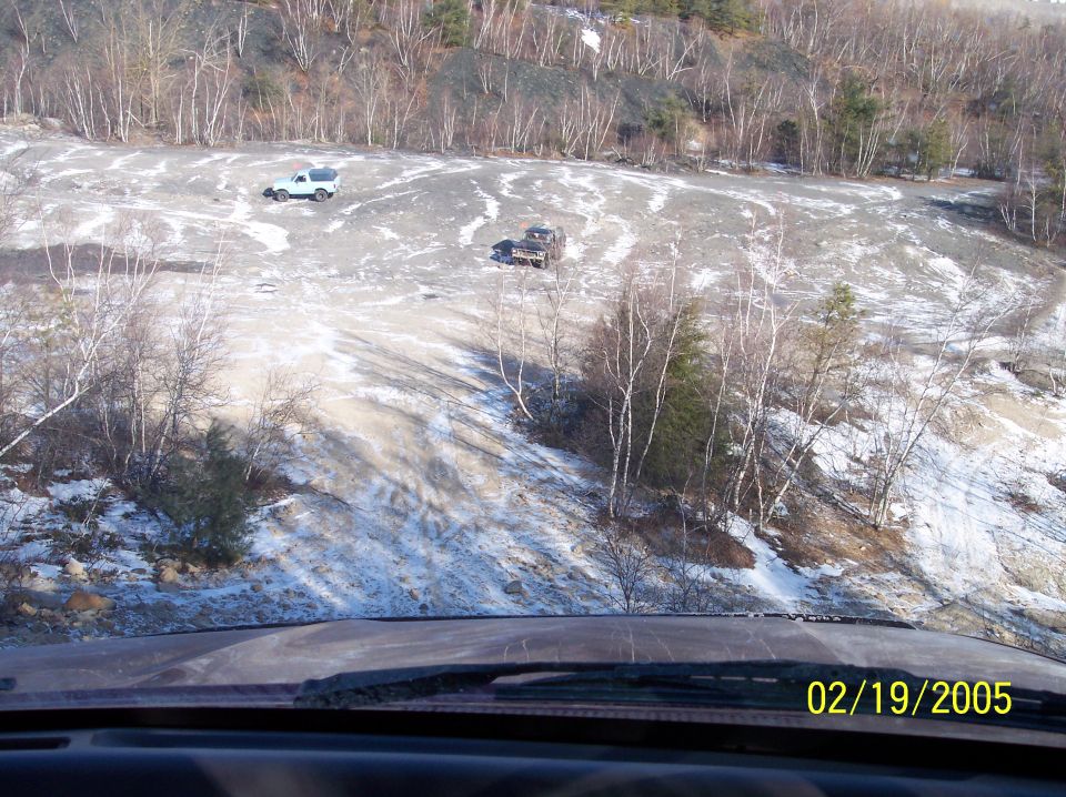 Two off-road vehicles driving in a quarry with snow patches on the ground. Date stamp reads 02/19/2005