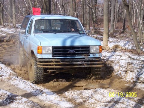 1995 Ford Bronco - 1995 Ford Bronco navigating a challenging muddy and snowy off-road course.