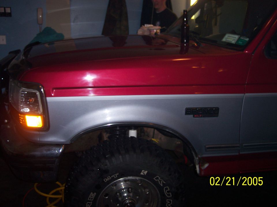 Red and silver Ford Bronco with off-road tires, front fender and headlight visible
