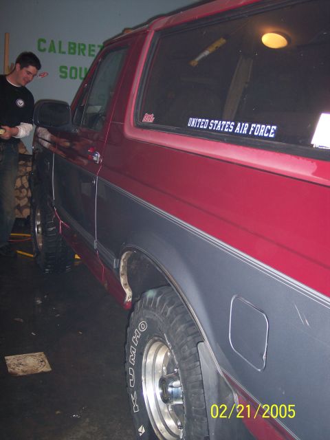 1995 Ford Bronco - A two-tone red and gray SUV is parked indoors, a United States Air Force sticker on the rear window.