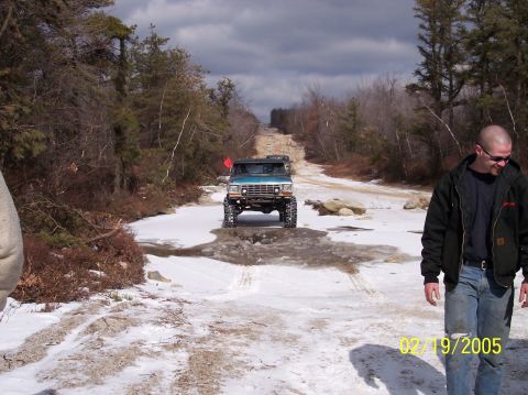 1995 Ford Bronco - A teal Ford Bronco navigates a snowy trail with another vehicle behind it.