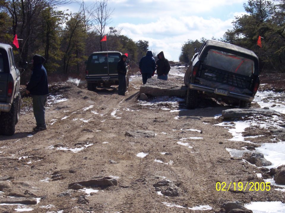 1995 Ford Bronco navigating a rocky, off-road trail with other vehicles present