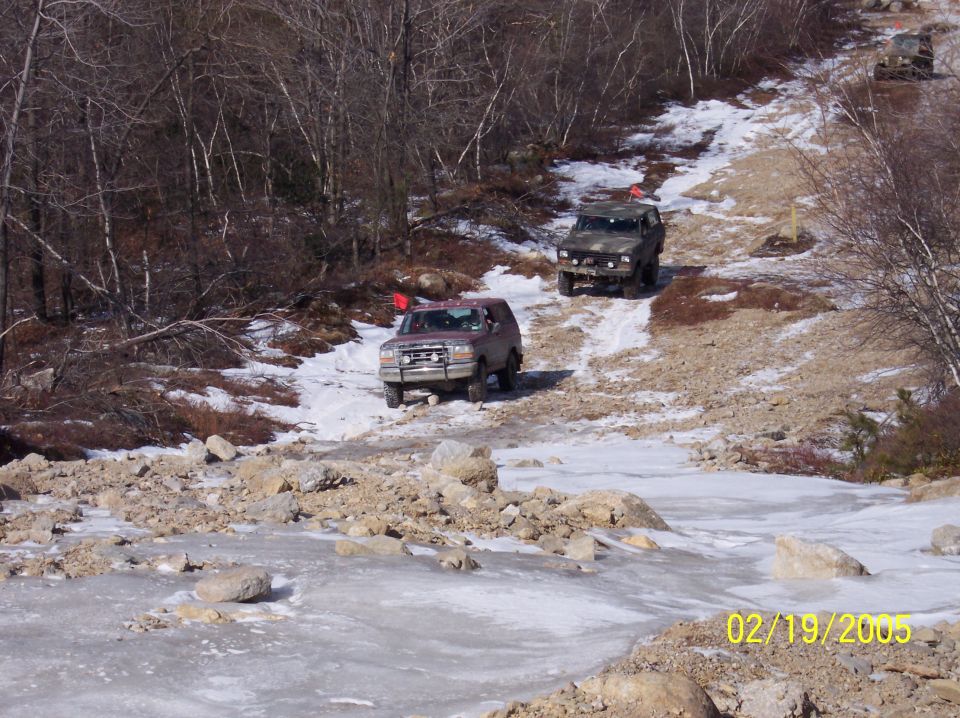 Red 1995 Ford Bronco on snowy trail with other SUVs