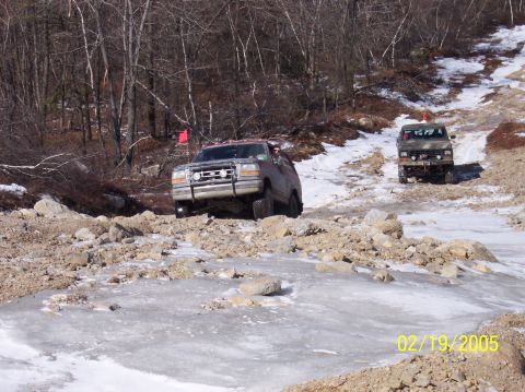 1995 Ford Bronco - Two SUVs tackle a challenging off-road trail in winter conditions.