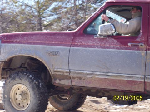 1995 Ford Bronco - Driver operating a 1995 Ford Bronco on a dirt path with trees in the background.