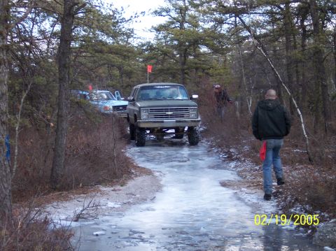 1995 Ford Bronco - Two SUVs navigate a wooded area with icy terrain.