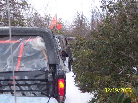1995 Ford Bronco - Several off-road vehicles are seen on a snowy trail surrounded by trees and brush.
