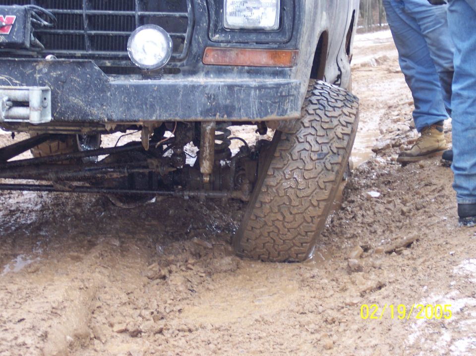 Front tire of black off-road vehicle stuck in mud, with date stamp 02/19/2005