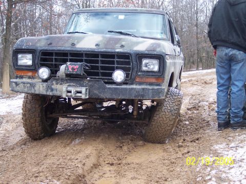 1995 Ford Bronco - Muddy Ford truck with winch and auxiliary lights, front view. Camouflage paint.