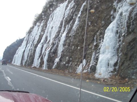 1995 Ford Bronco - Winter scene with icicles on a cliff face beside a highway. A car is visible in the distance.
