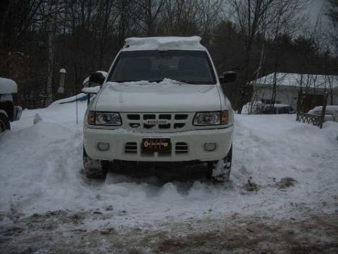 2000 Isuzu Rodeo - A white 2000 Isuzu Rodeo is parked in a snowy landscape, with trees and a house visible in the background.