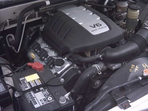 2000 Isuzu Rodeo - Close-up view of a vehicle's engine bay, showing the V6 engine and battery.