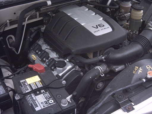 Transverse V6 DOHC 24-valve engine bay with black engine cover and Delco battery
