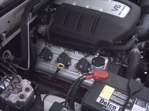 2000 Isuzu Rodeo - Close-up view of an engine bay, a V6 DOHC engine cover and a battery with visible 'SUPERMOTORS' branding.