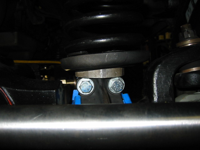 Close-up of suspension components with blue spacers and silver bolts