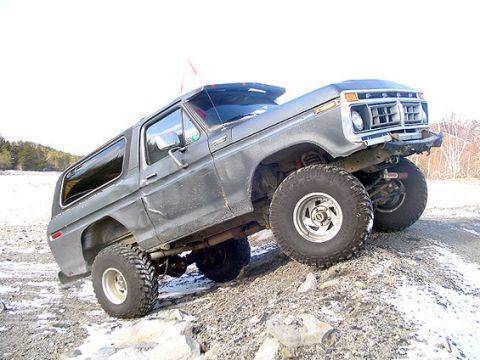 1995 Ford Bronco - This lifted Ford Bronco is shown off-road on a gravelly incline with scattered snow.