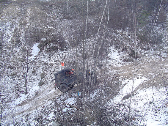 dark SUV driving up a snowy, wooded hill