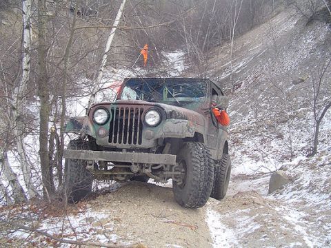1995 Ford Bronco - A Jeep CJ-7 navigates a challenging off-road path in a winter landscape.