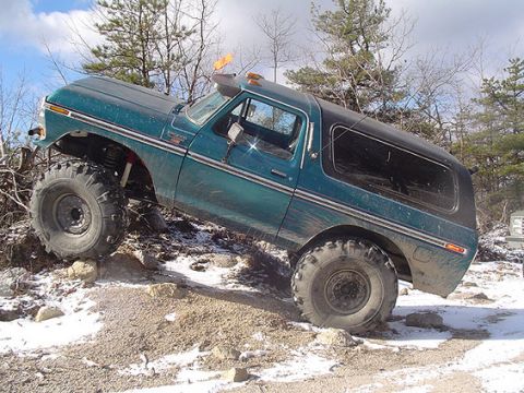 1995 Ford Bronco - This modified SUV navigates a rocky, snow-dusted trail, its off-road capabilities.
