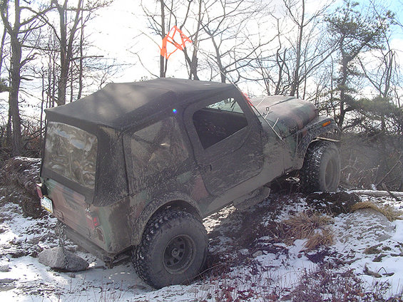 Camouflaged Jeep Wrangler TJ with soft top on snowy terrain