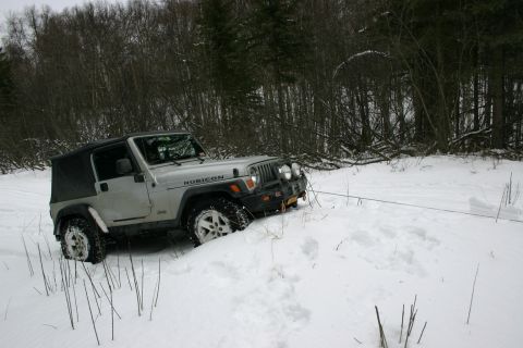 2003 Jeep TJ - A silver Jeep Wrangler TJ is partially buried in snow, with a tow rope extending to the right.