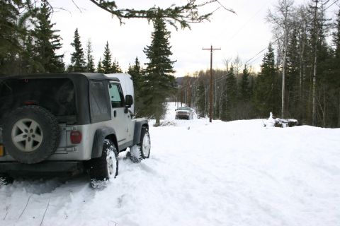 2003 Jeep TJ - A Jeep Wrangler navigates a snow-covered road, with another vehicle visible in the distance.
