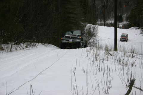 2003 Jeep TJ - Two off-road vehicles navigate a snow-covered path through a wooded area.
