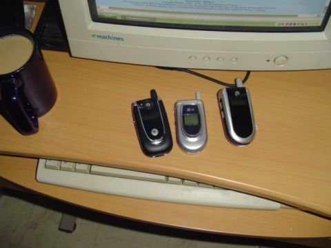 1993 Ford Bronco - Three cell phones are arranged on a wooden desk next to a computer monitor and a mug of coffee.