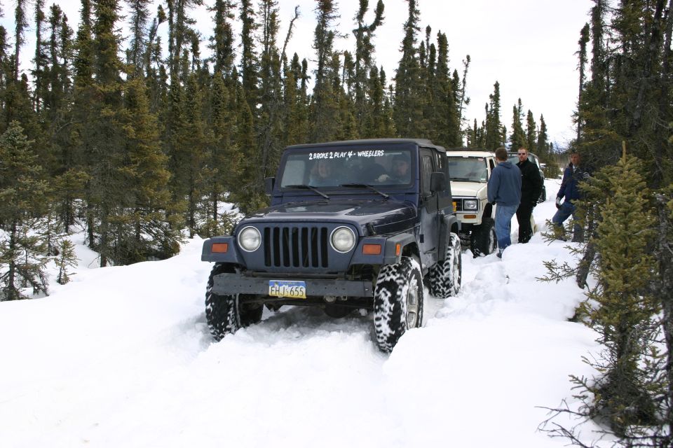 Dark blue Jeep TJ driving through snow with another Jeep behind it