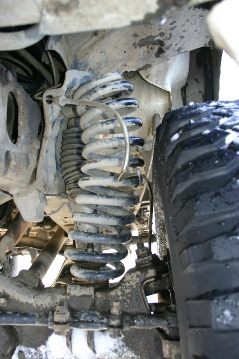 2003 Jeep TJ - This image shows the suspension components of a vehicle, including the coil spring and part of the tire.